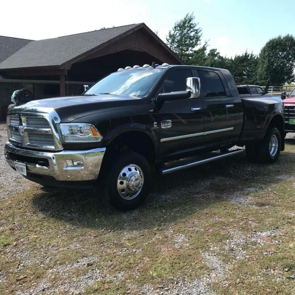 Black pickup truck parked in a driveway beside a house on a sunny day