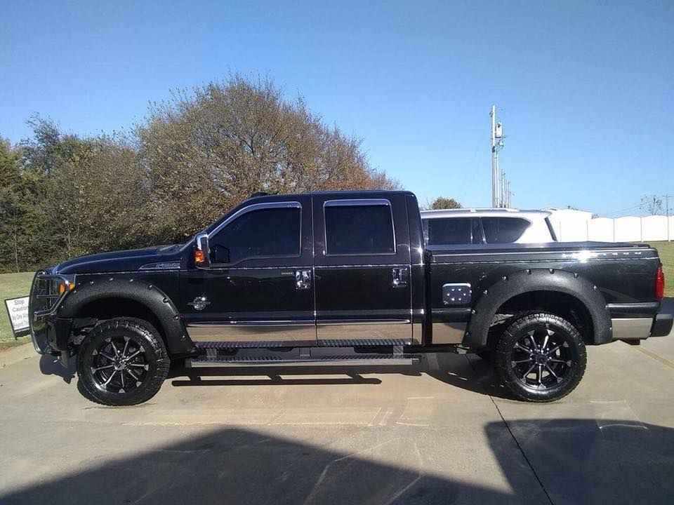 Black lifted crew cab pickup truck parked outdoors on a sunny day