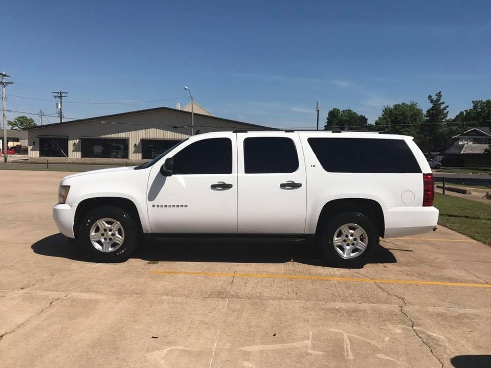 White SUV parked on a sunlit lot near a low building under a clear blue sky