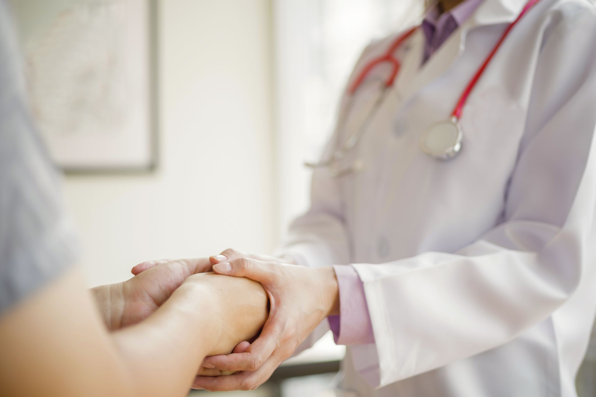 Doctor holding a patient’s hands in a bright clinic, offering reassurance