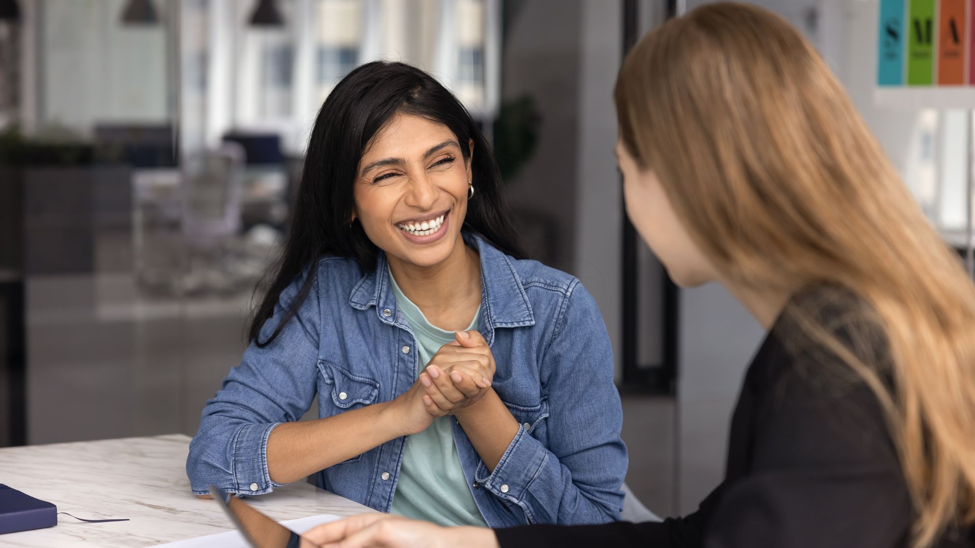 Doctor reviewing notes with a seated patient in a bright clinic office