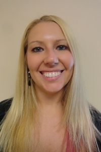 Smiling blonde woman against a plain beige background