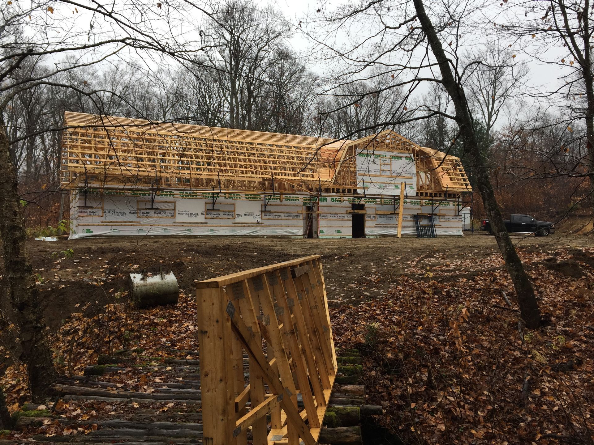 Une structure en bois en construction dans une zone boisée, avec au premier plan une structure en bois sur un pont.