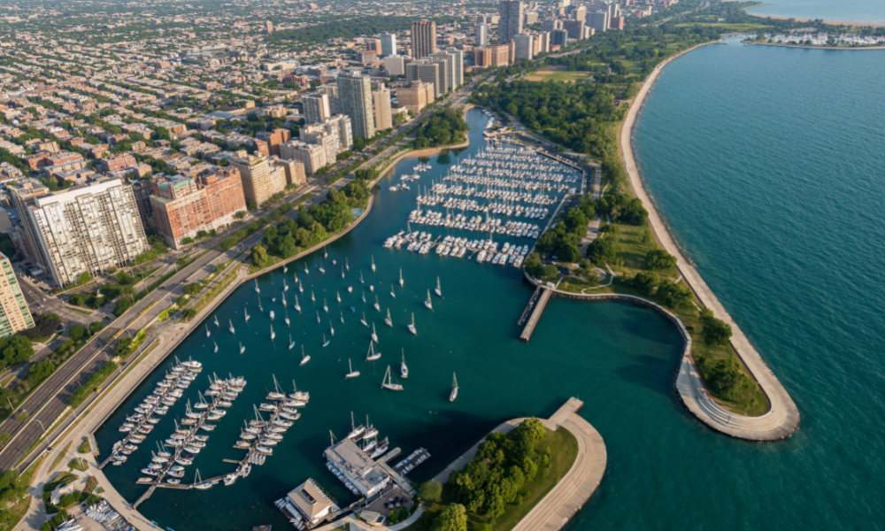 An aerial view of a marina filled with boats and a city in the background.