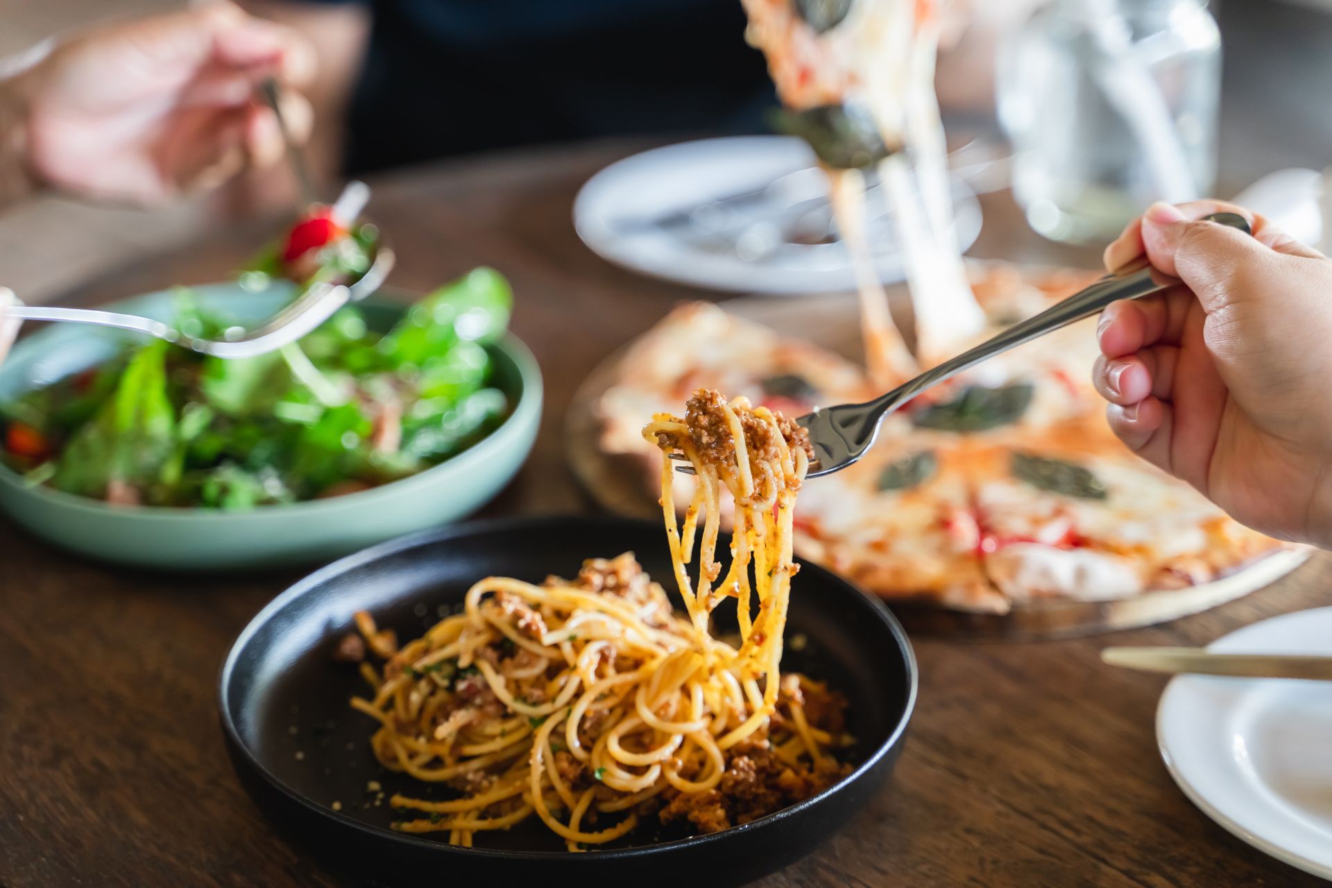 Family-style Italian dinner with spaghetti, pizza, and salad