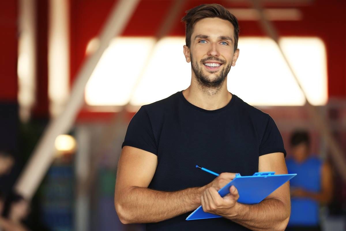 Personal trainer holding clipboard with training plan in gym near Lexington, Kentucky (KY)