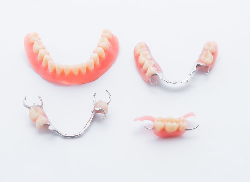Four sets of dentures on a white background, showing upper and lower full and partial sets.