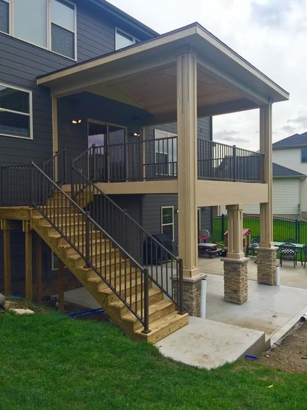 Covered outdoor stairway and elevated deck on a house with black railings and wooden steps