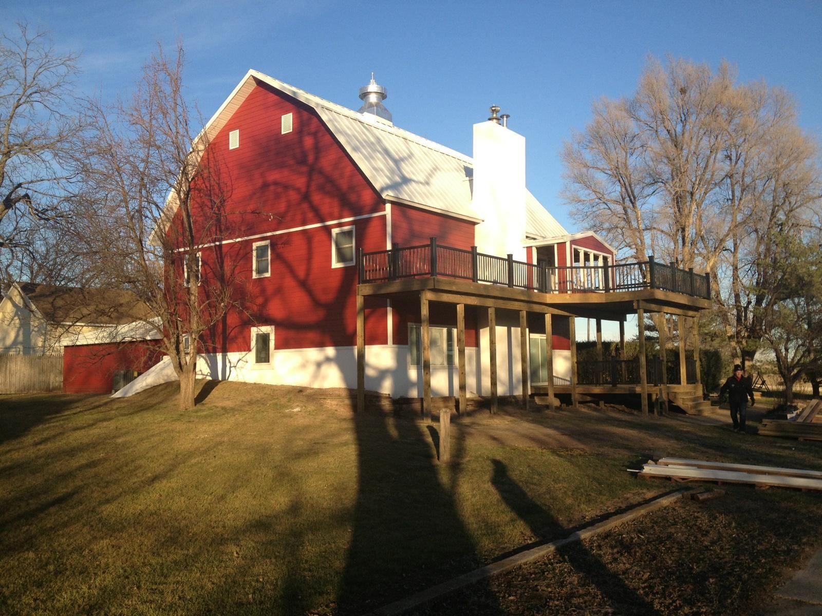 Red barn-style house with white porch and leafless trees in winter sunlight