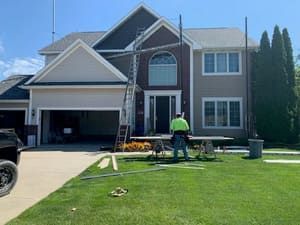Suburban house with a worker mowing the front lawn on a sunny day