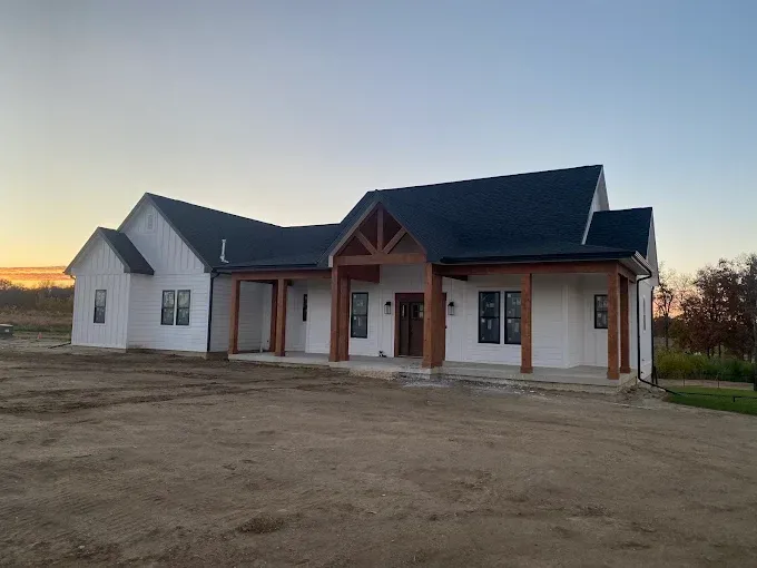 New single-story house with a dark roof and covered porch at sunset