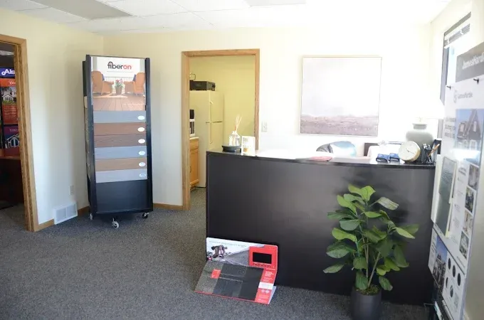 Office lobby with reception desk, brochure stand, and potted plant in carpeted room