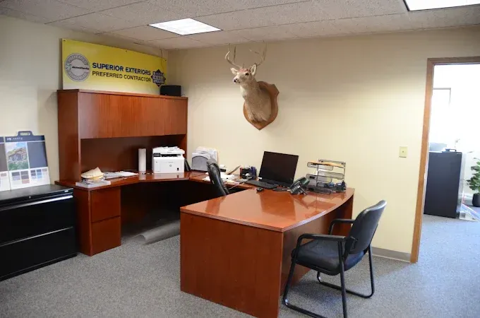 Office with wooden desk, cabinets, computer, and mounted deer head on a beige wall.