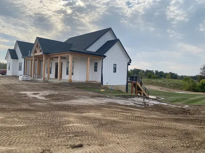 New white house under construction on a dirt lot with a small porch and stairs