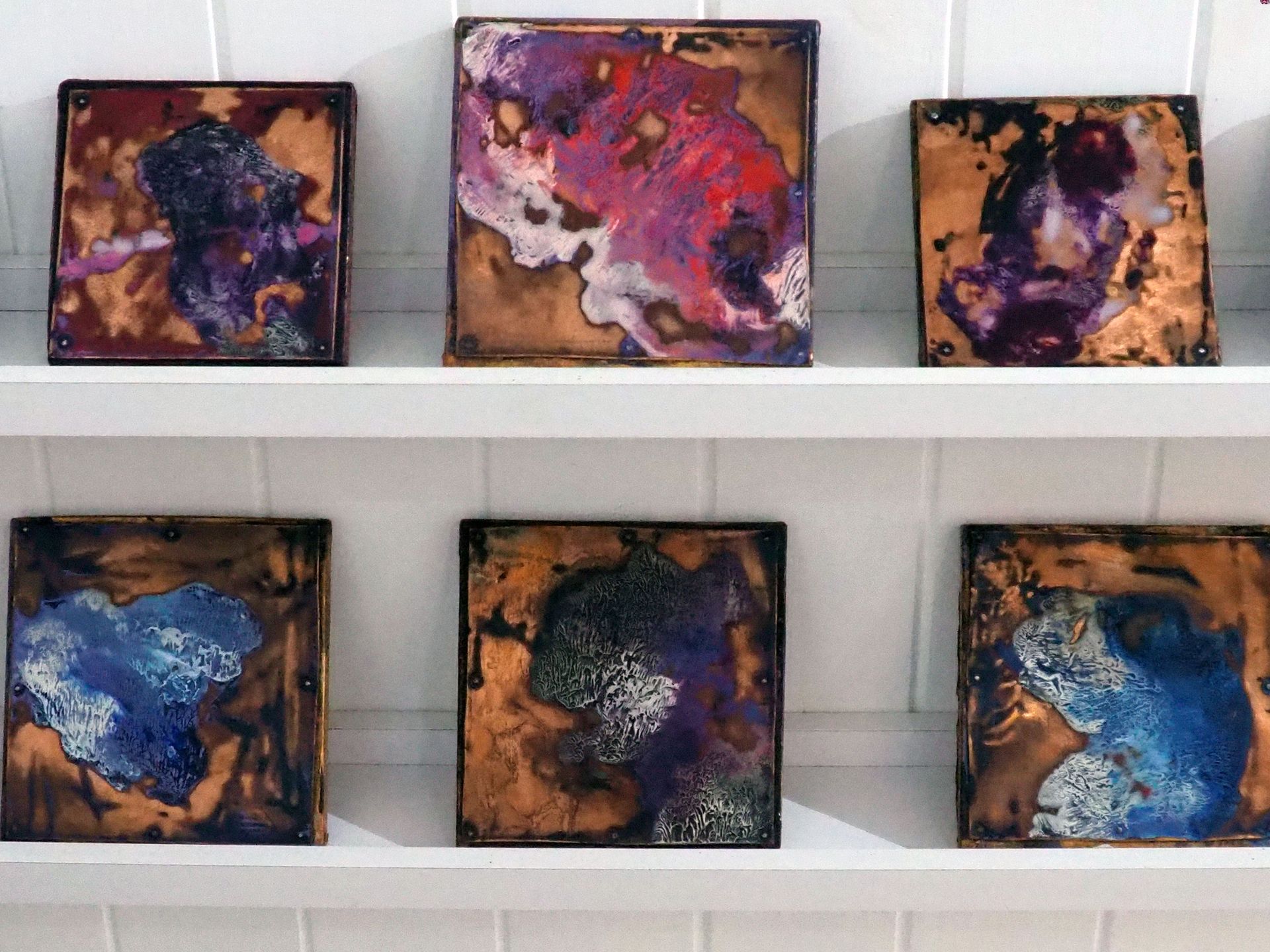 Six small copper squares with different coloured blobs of paint on.. white and blue, purple and white.. 