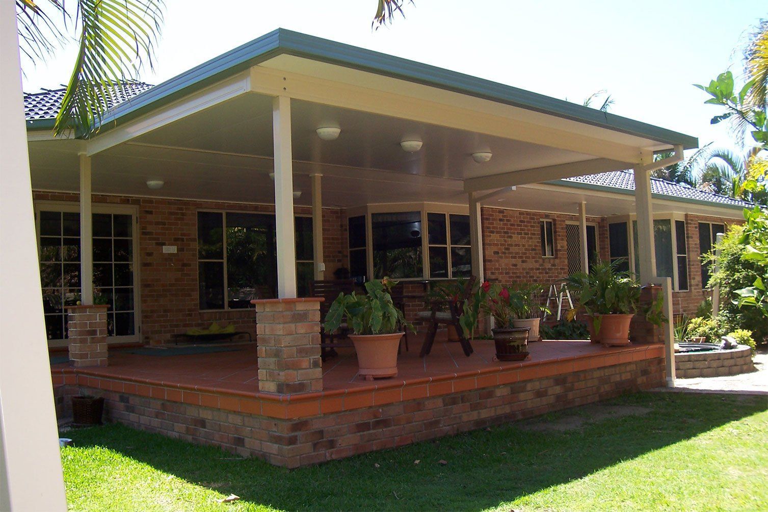 Brick house with a covered porch, potted plants, and a green lawn in front