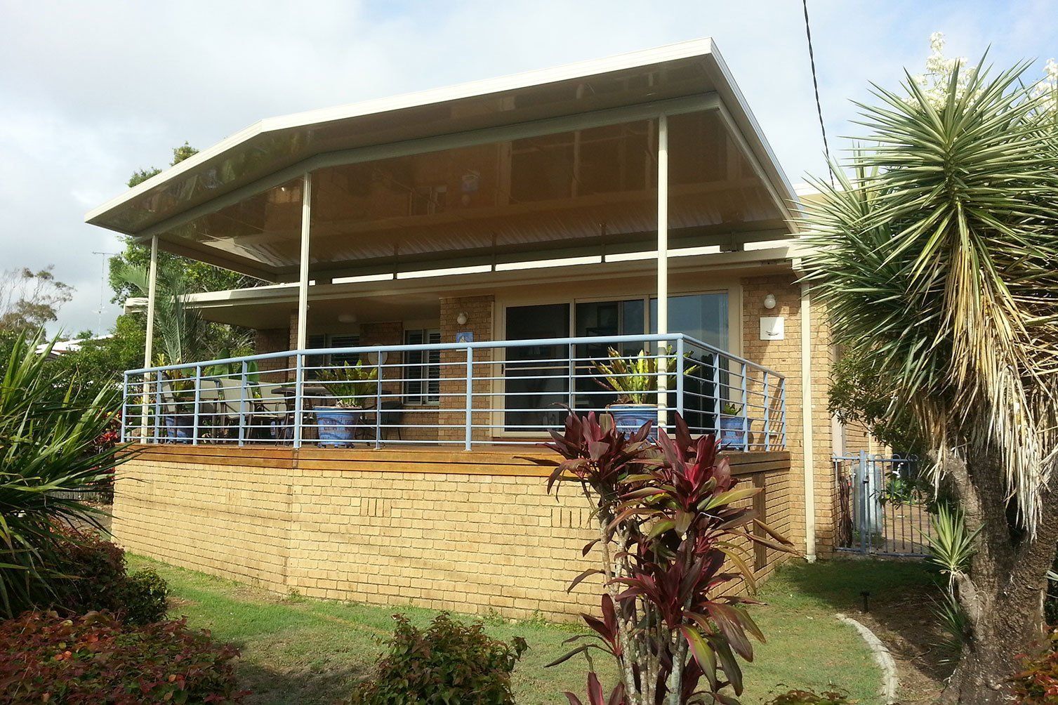 Modern house with a covered porch, metal railing, and landscaped front yard