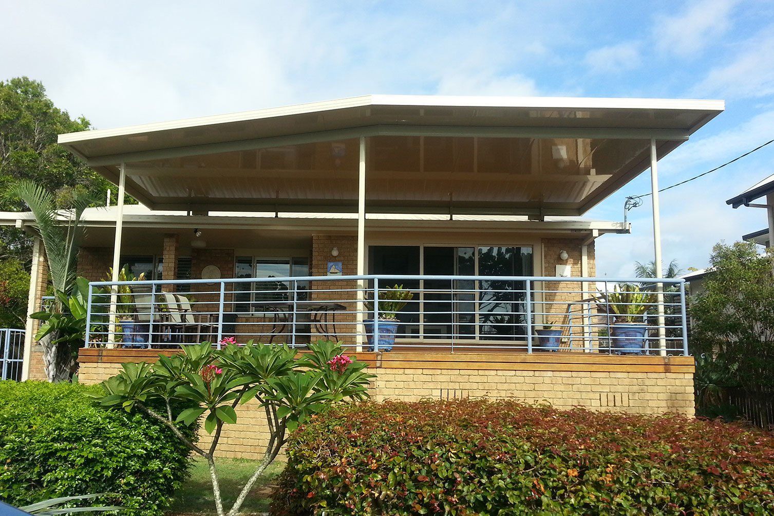 Modern building with a covered porch, blue railing, and landscaped bushes in front