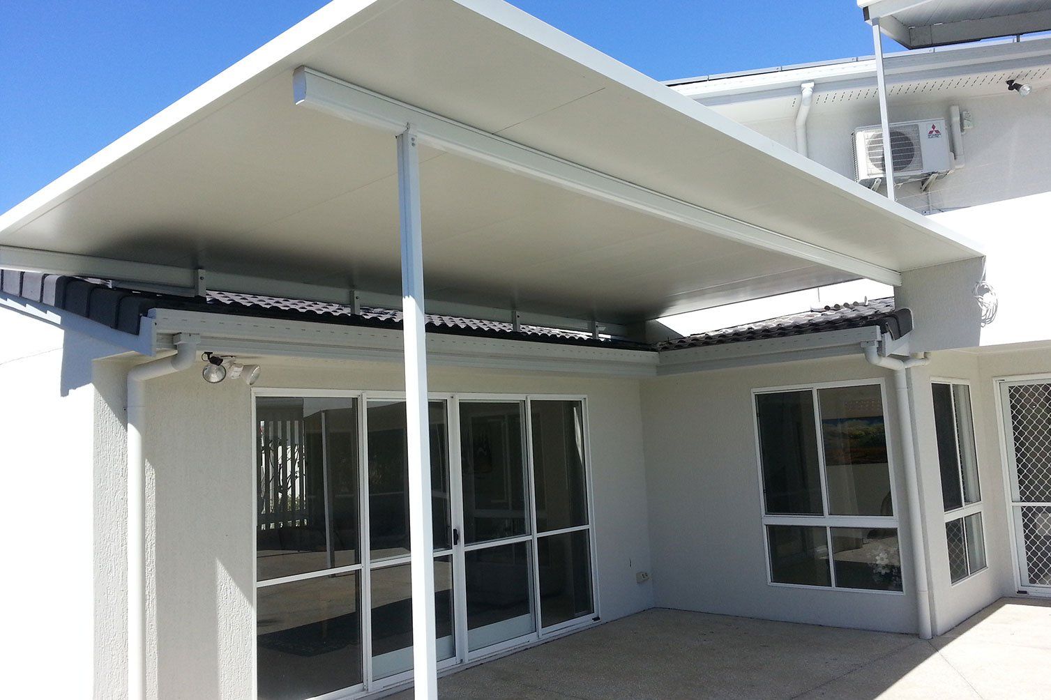 Covered patio with a white awning, sliding glass doors, and large windows on a building exterior