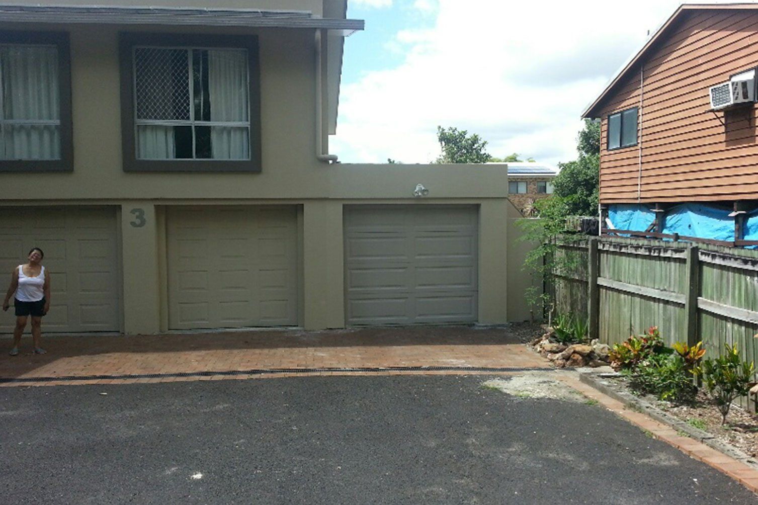 House front with three garage doors and a person standing by the entrance