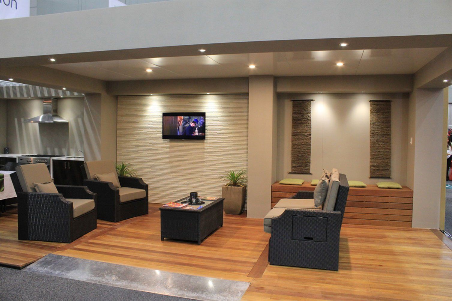 Modern lounge with wicker chairs, sofa, coffee tables, wood flooring, and wall-mounted TV