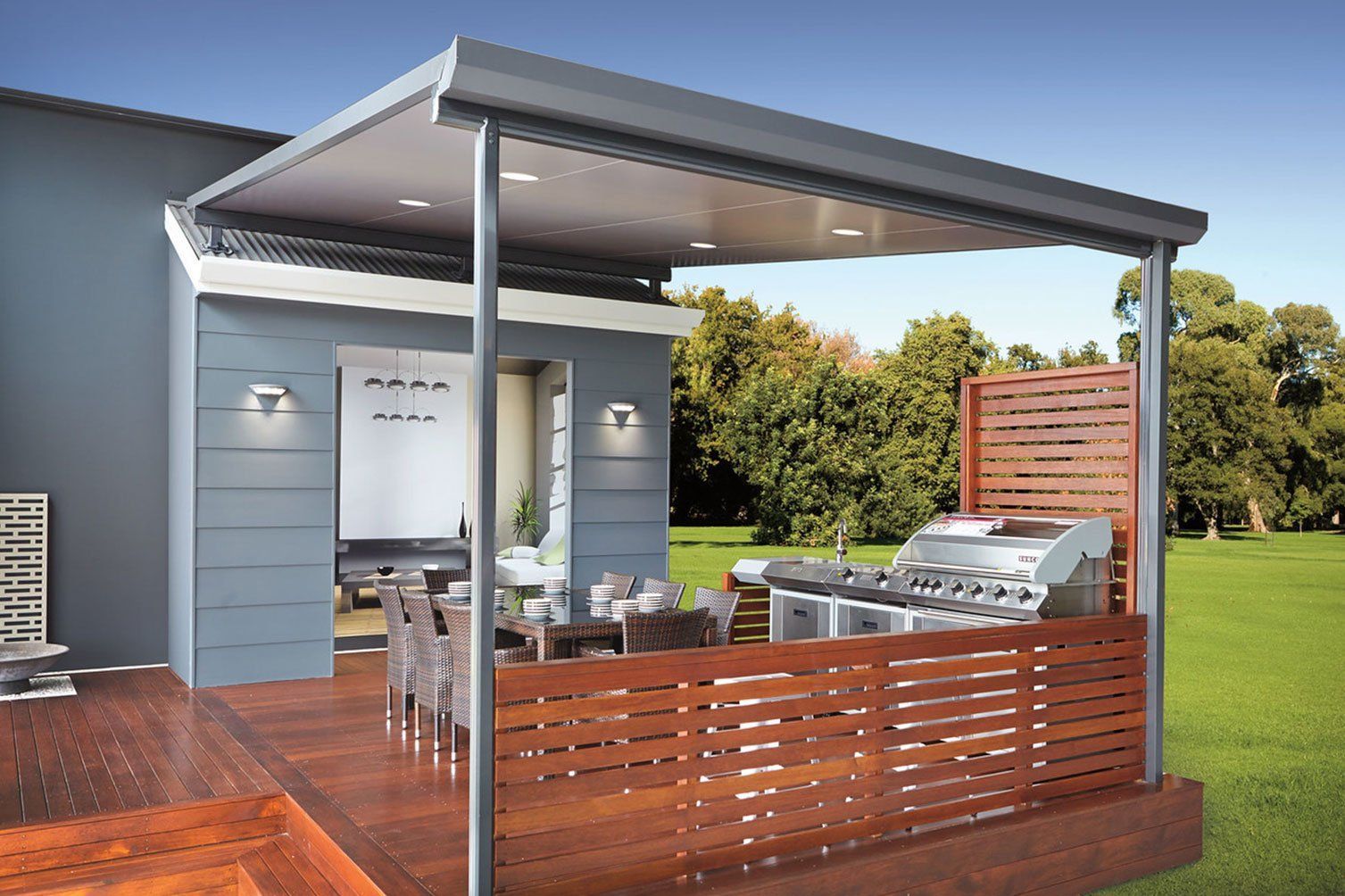 Modern patio deck with covered pergola, outdoor dining table, grill, and wooden privacy fence beside a house