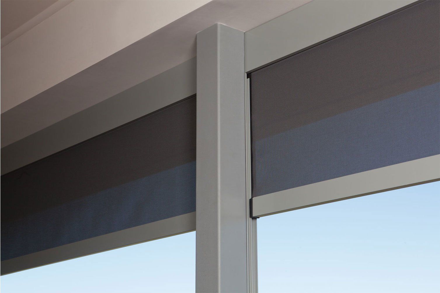 Close-up of a window with dark mesh shades and a white vertical frame against blue sky
