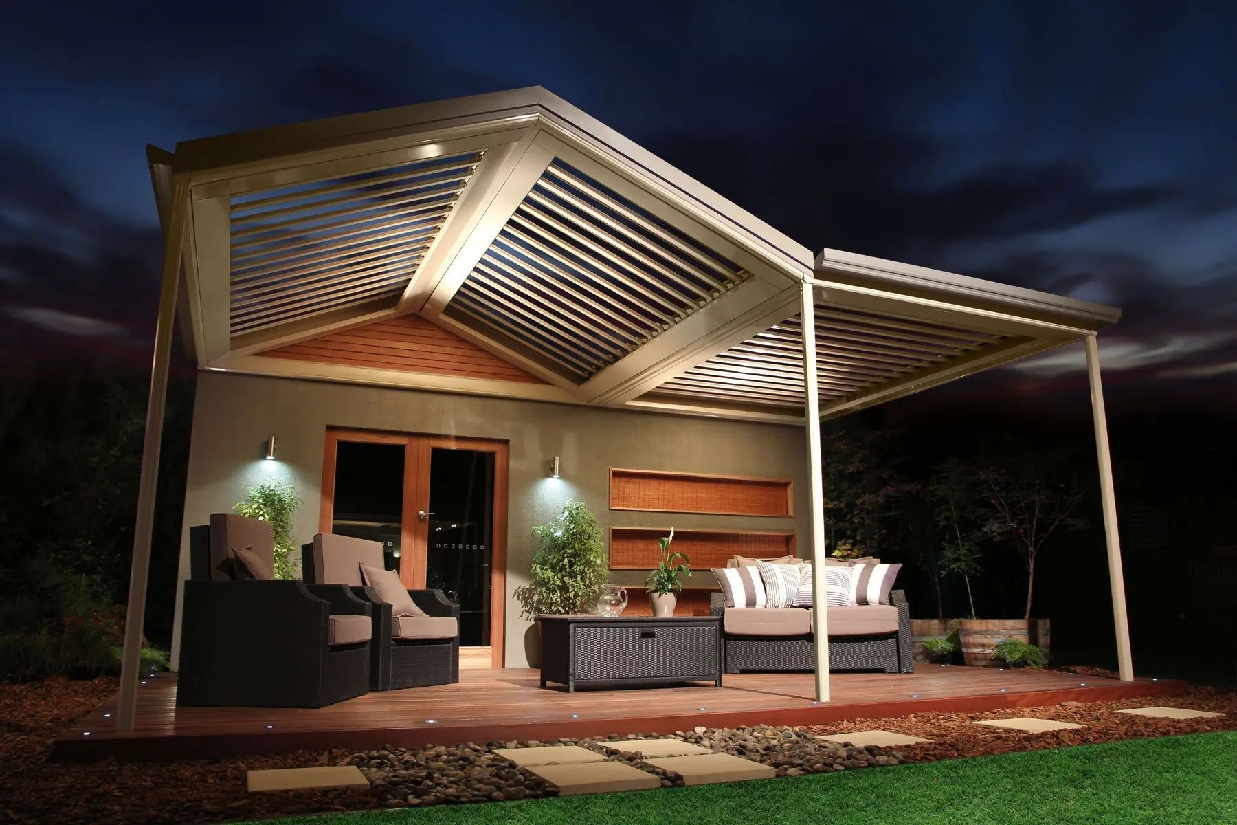 Modern outdoor patio with pergola, seating, warm lighting, and brick pavers at dusk