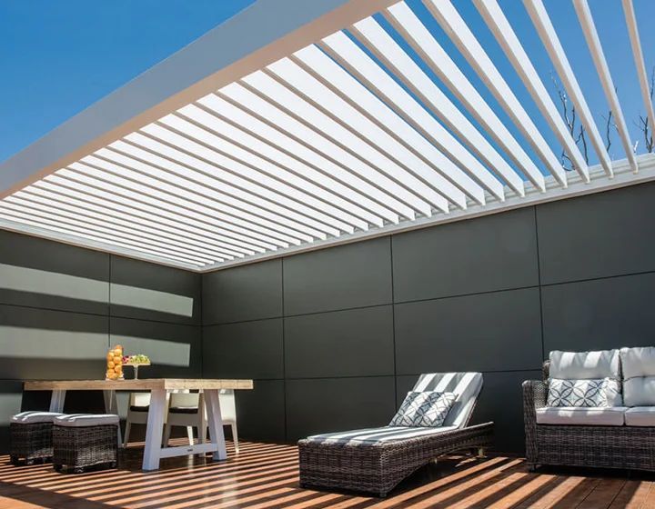 Modern rooftop patio with striped pergola, dark sectional seating, lounge chairs, and a small table