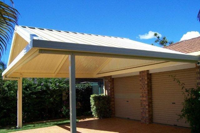 Covered carport attached to a brick house with a white metal roof and supporting posts