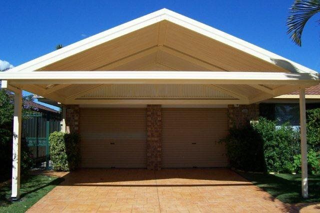 Two-car carport with a beige roof and closed roller doors in front of a house