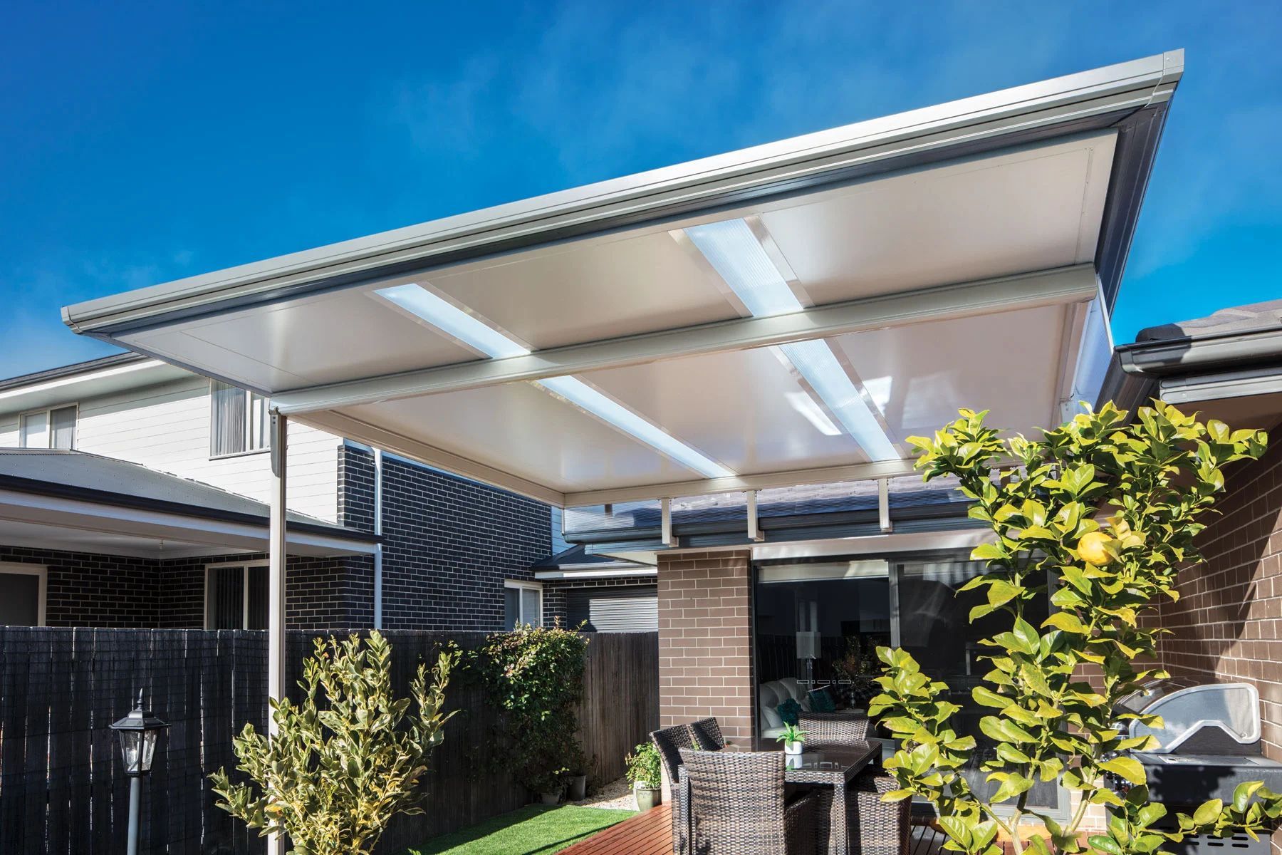 Modern patio with white canopy roof, outdoor seating, and a sunny garden courtyard