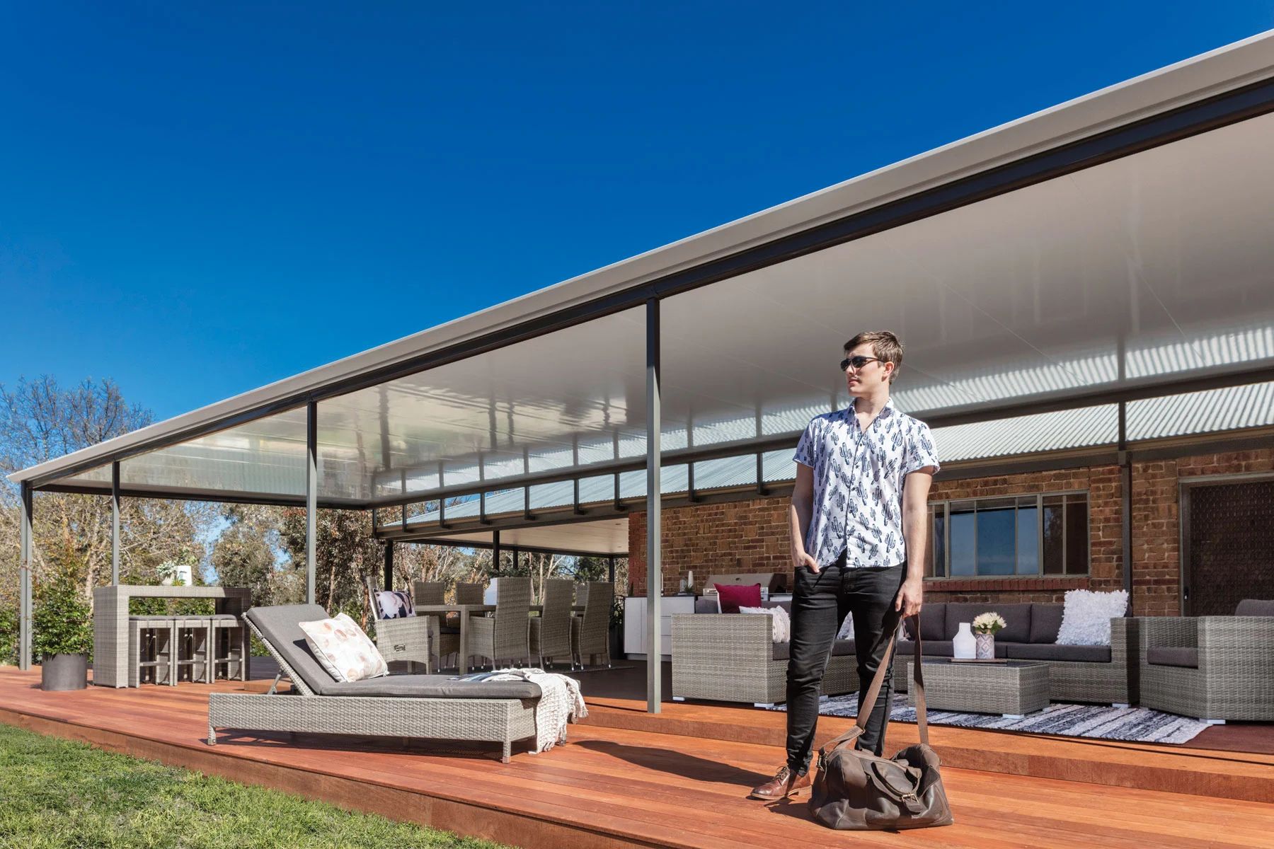 Person on a scooter on a covered patio with outdoor lounge chairs and a brick house backdrop