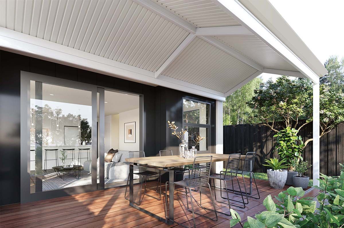 Covered patio with outdoor dining table, sliding glass doors, and potted plants in a sunlit backyard