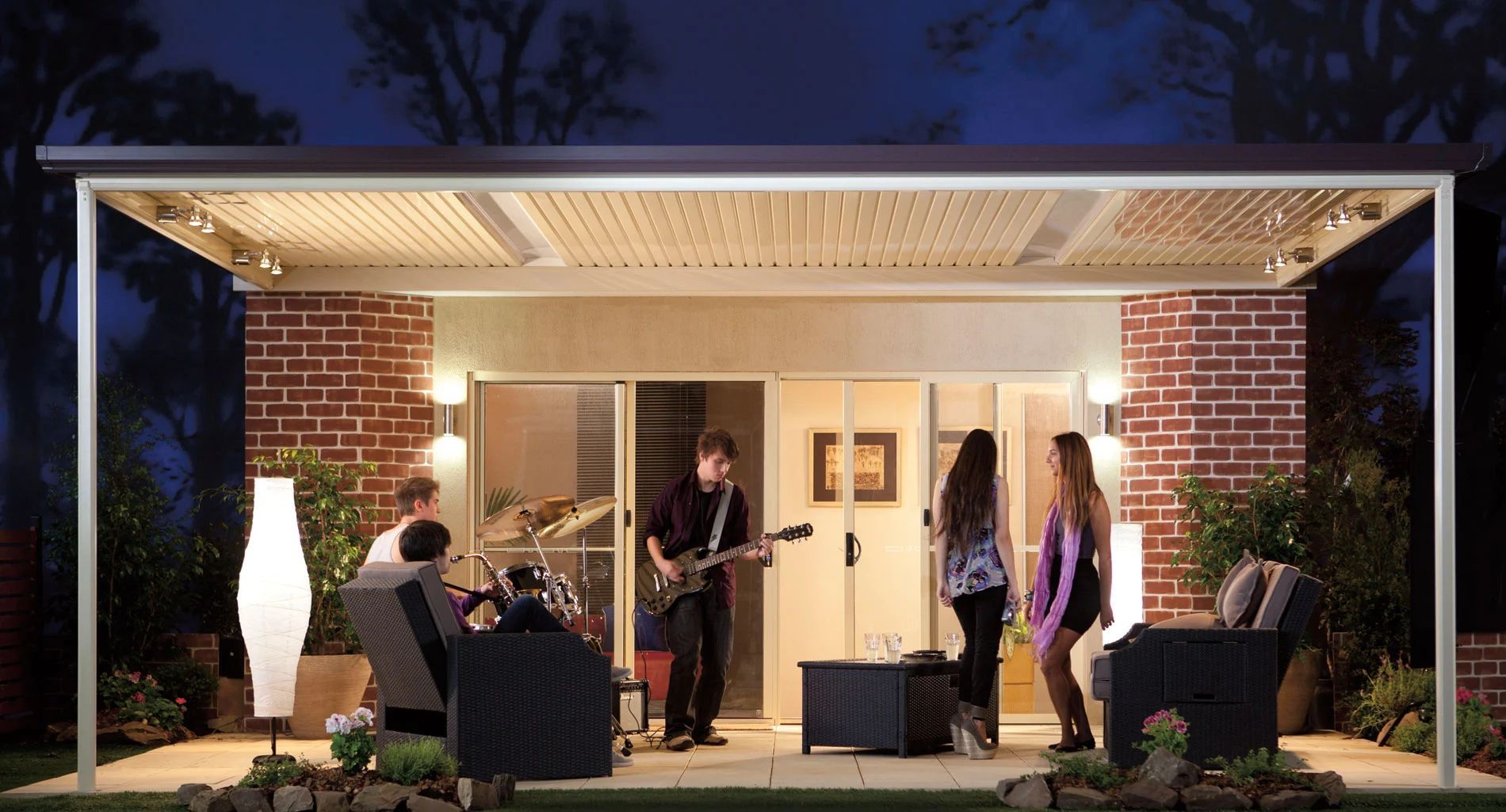 Outdoor patio performance under a modern canopy, with musicians and seated audience at night