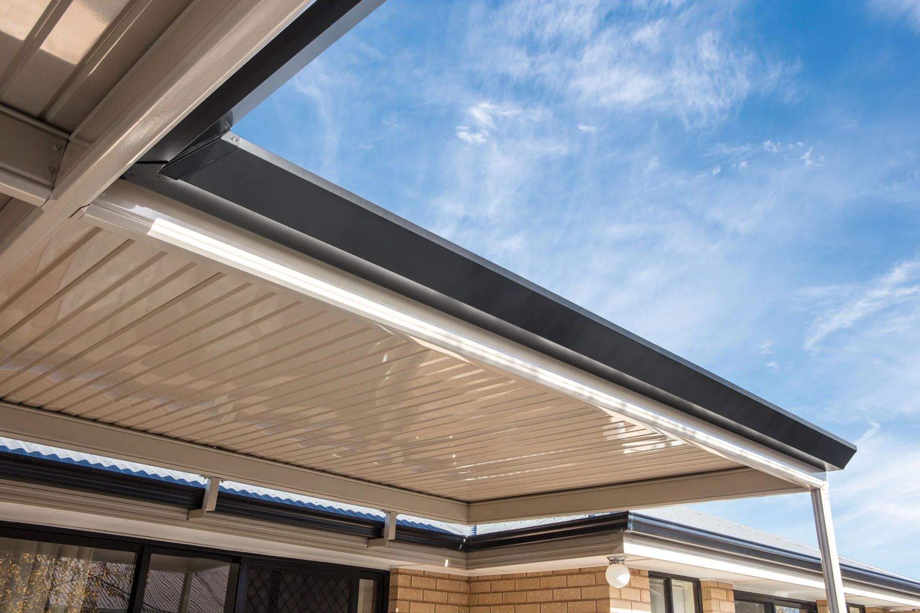 Covered outdoor patio with beige retractable awning under a blue sky