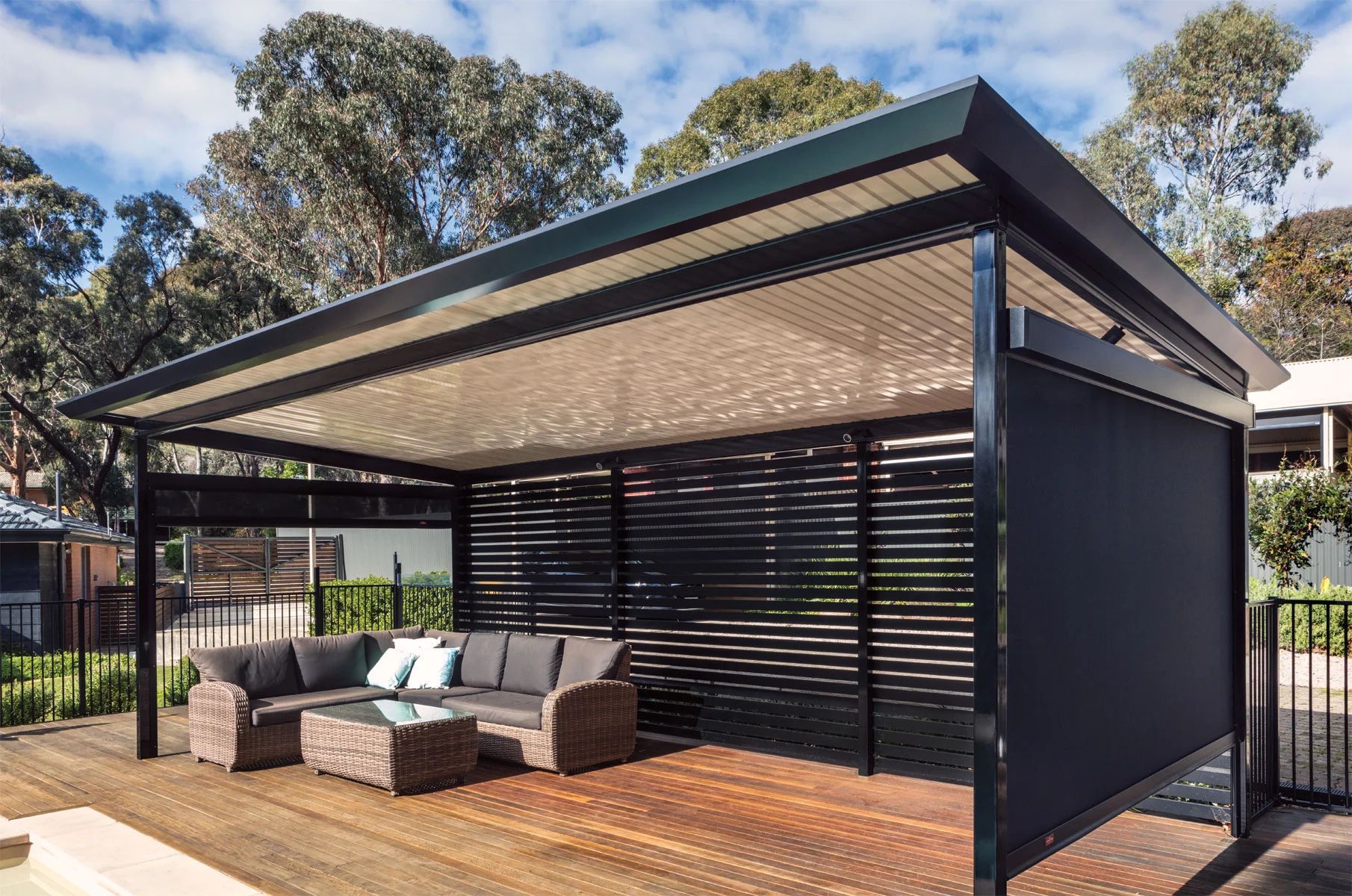 Modern backyard pergola with louvered roof, outdoor sofa, and timber deck in sunlight