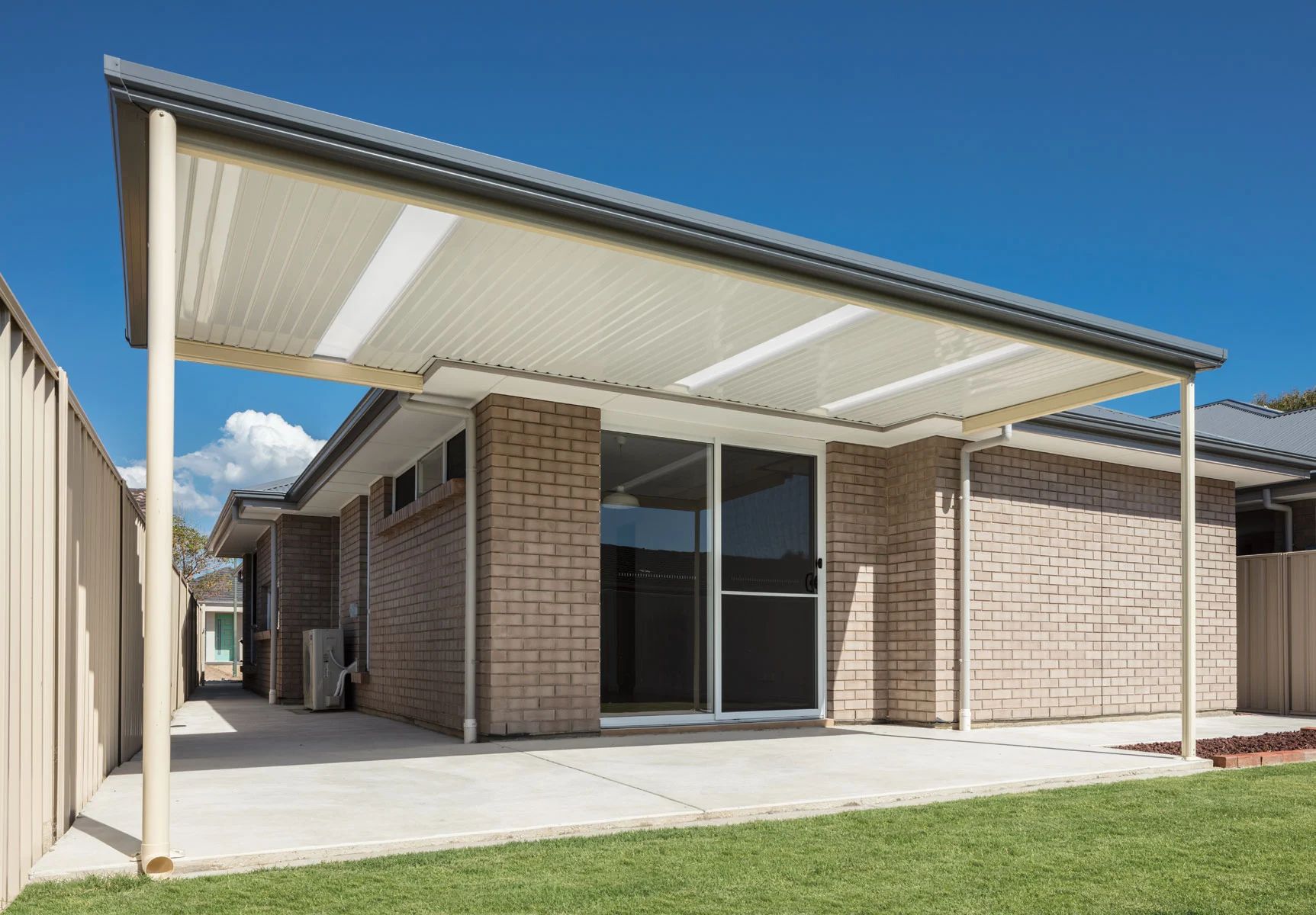 Modern brick house with a covered patio and large sliding glass doors under a white pergola