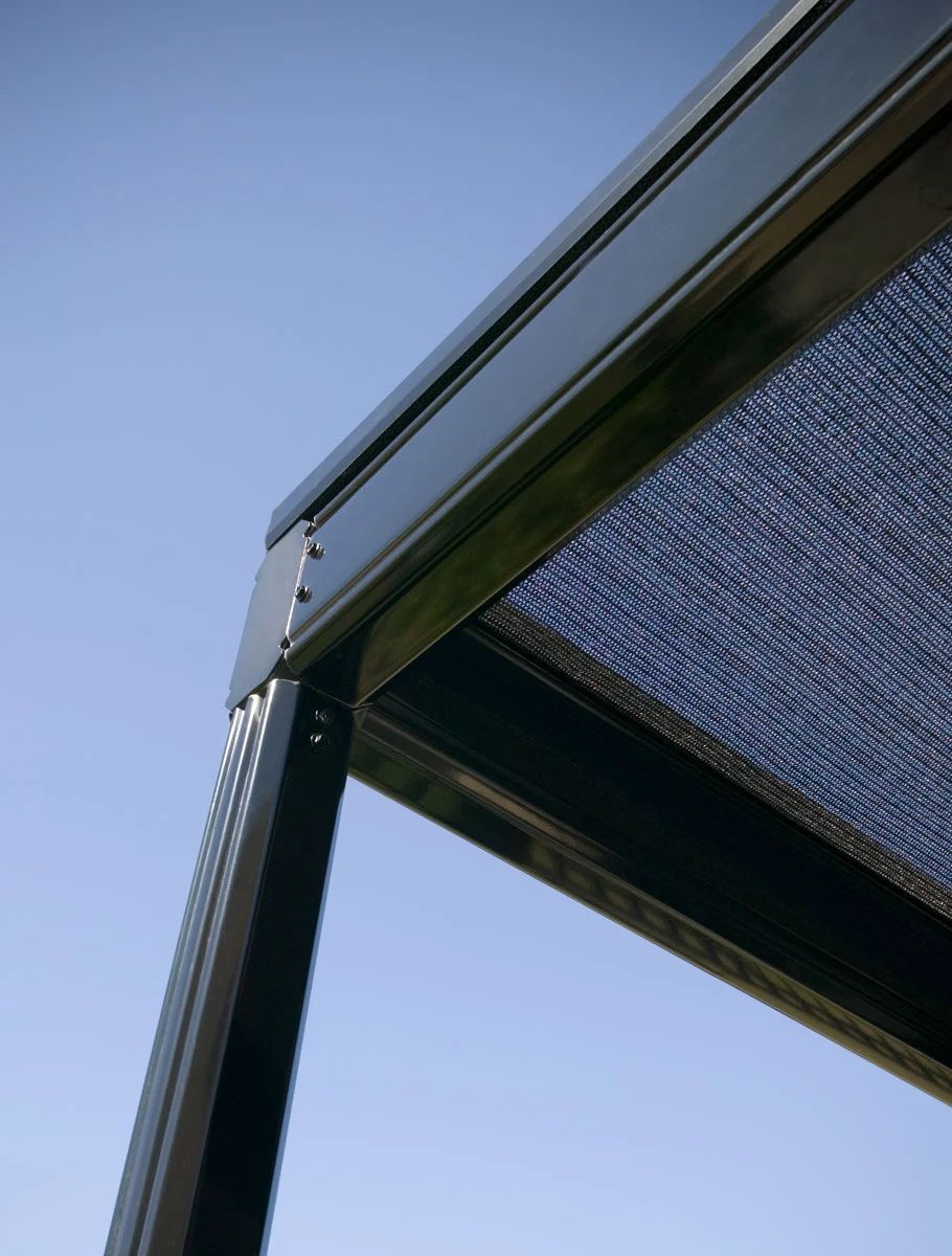 Close-up of a metal awning frame with a black mesh canopy against a blue sky