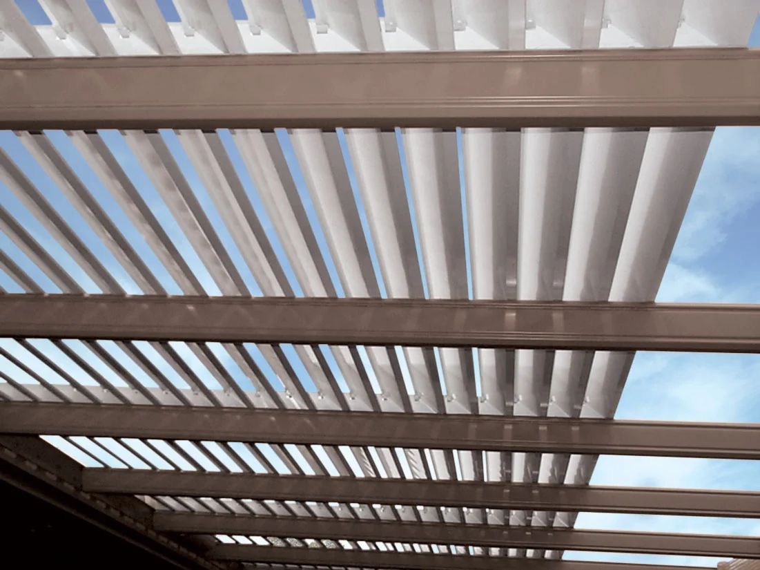 Wooden pergola slats with white slats above, viewed from below against the sky