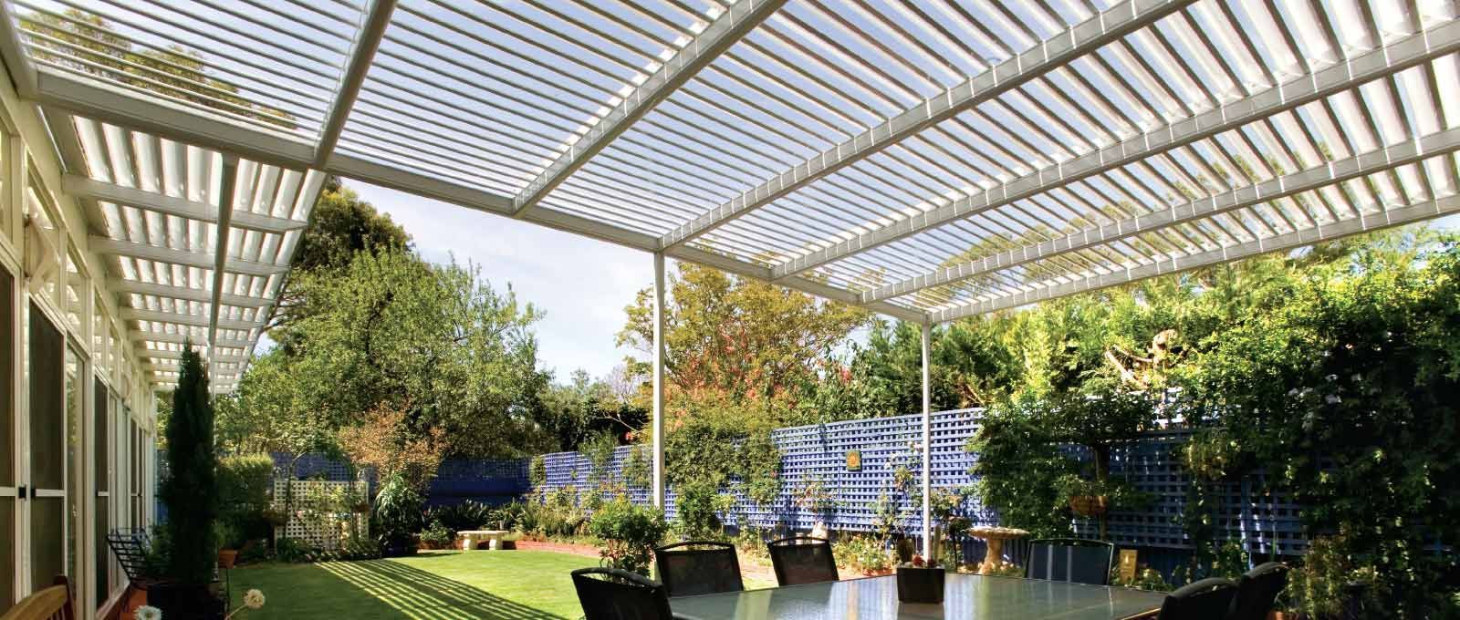 Patio garden with potted plants under a white pergola in bright sunlight