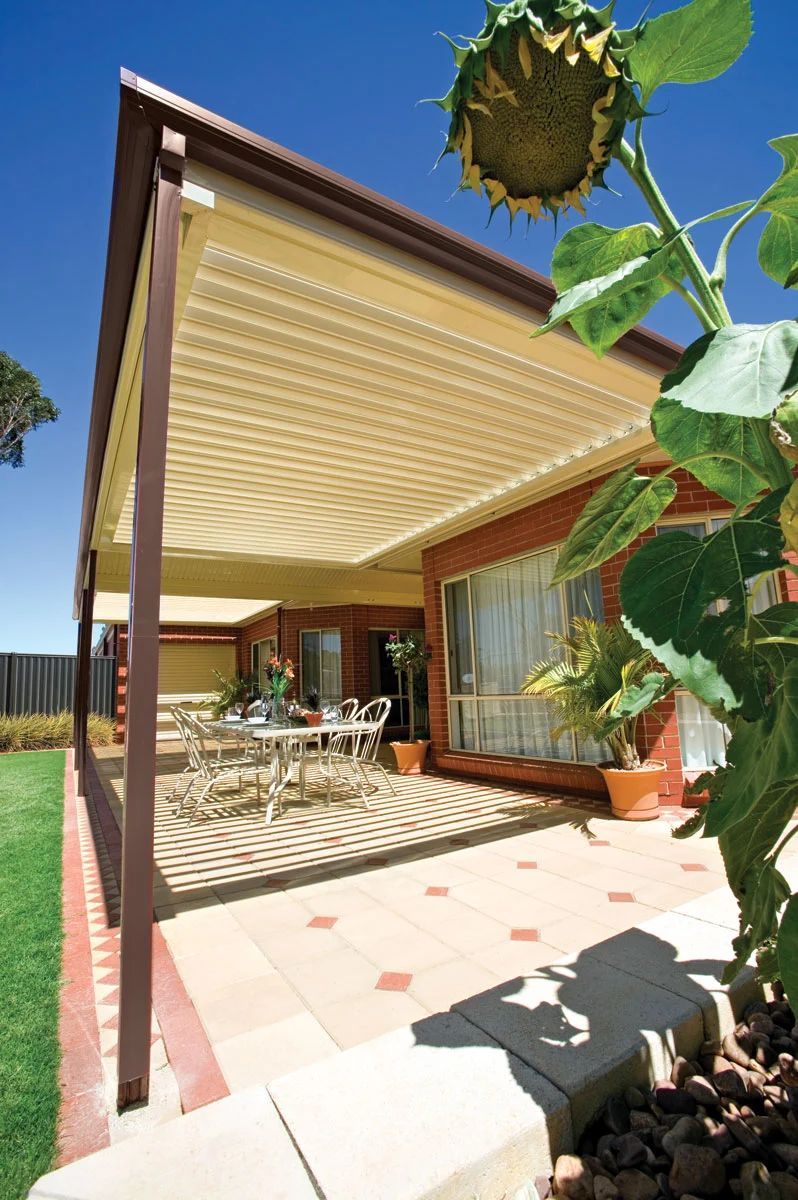 Covered patio with dining table, striped awning, and sunflower in the foreground