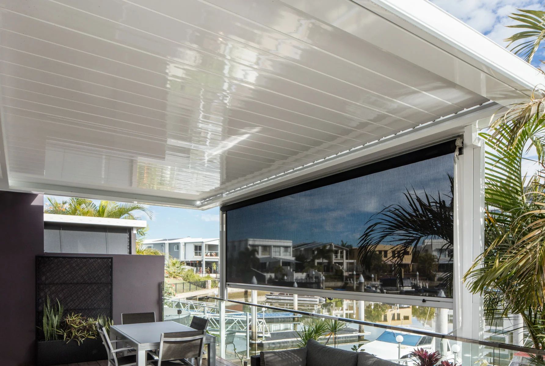 Covered patio with glass railing and outdoor dining area overlooking a residential neighborhood