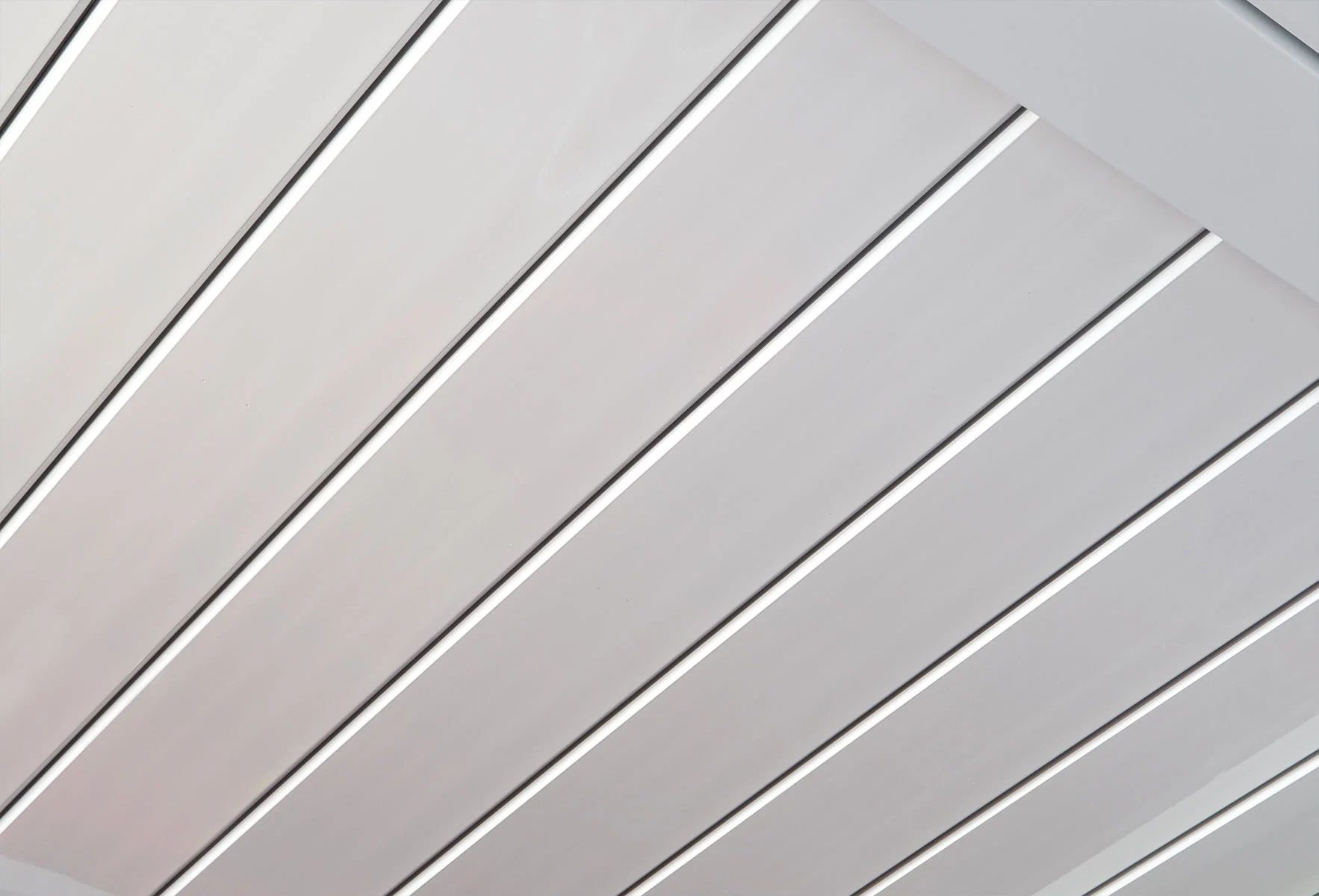 Diagonal white ceiling panels with narrow dark seams in a geometric pattern