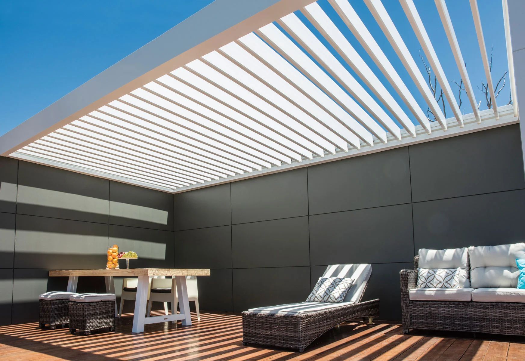 Modern rooftop patio with pergola, striped lounge chairs, table, and black walls under a blue sky