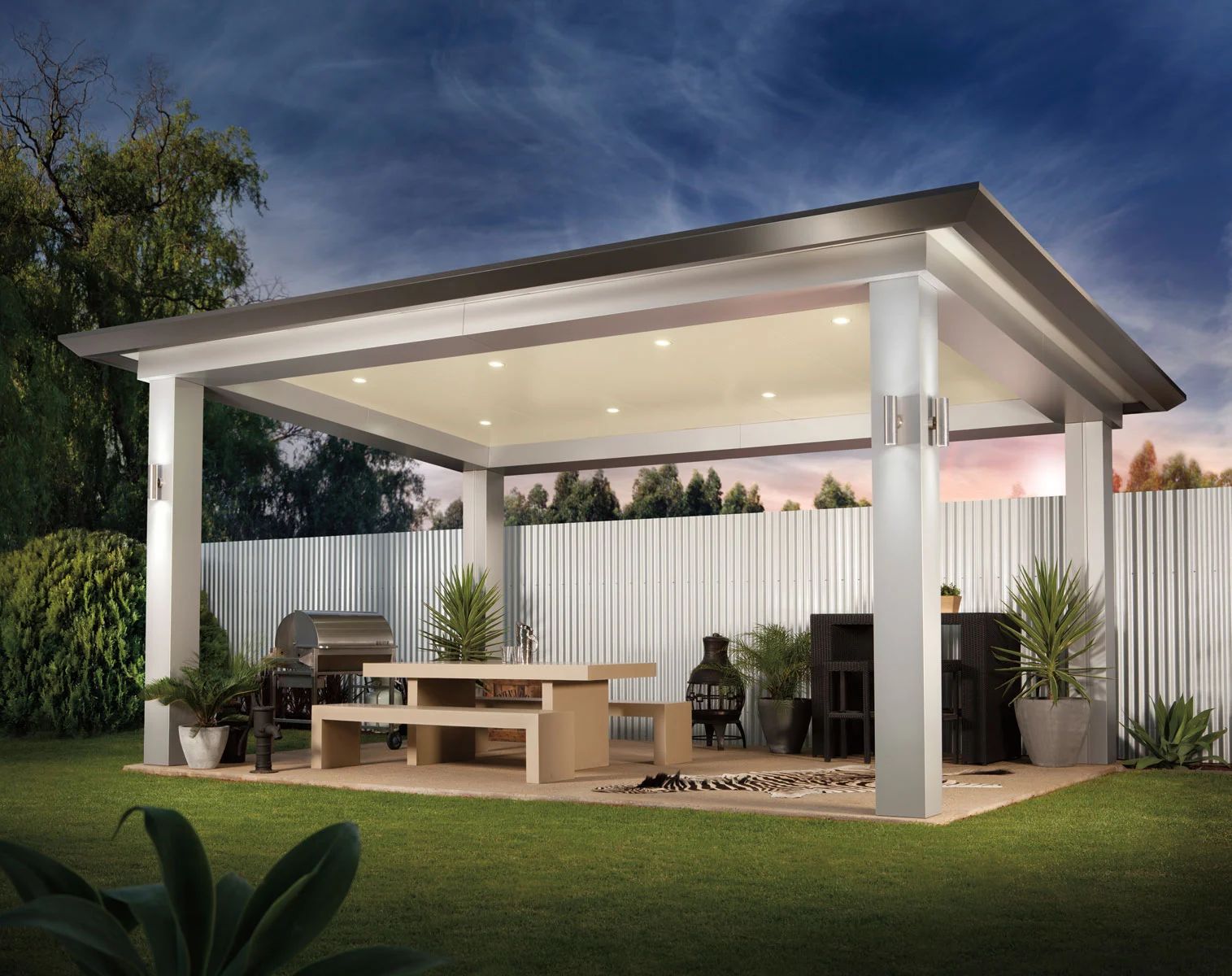 Modern outdoor patio with a covered seating area, white columns, warm lights, and a wooden table at dusk