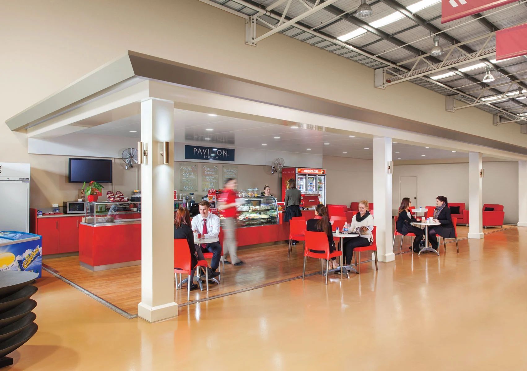Bright red casual dining area with people seated at tables in a modern indoor food court