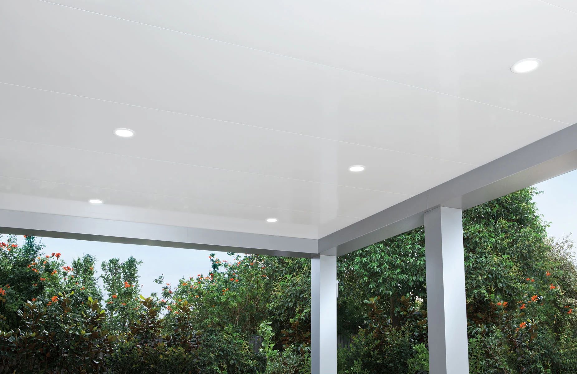 White patio ceiling and posts beside lush green trees outdoors