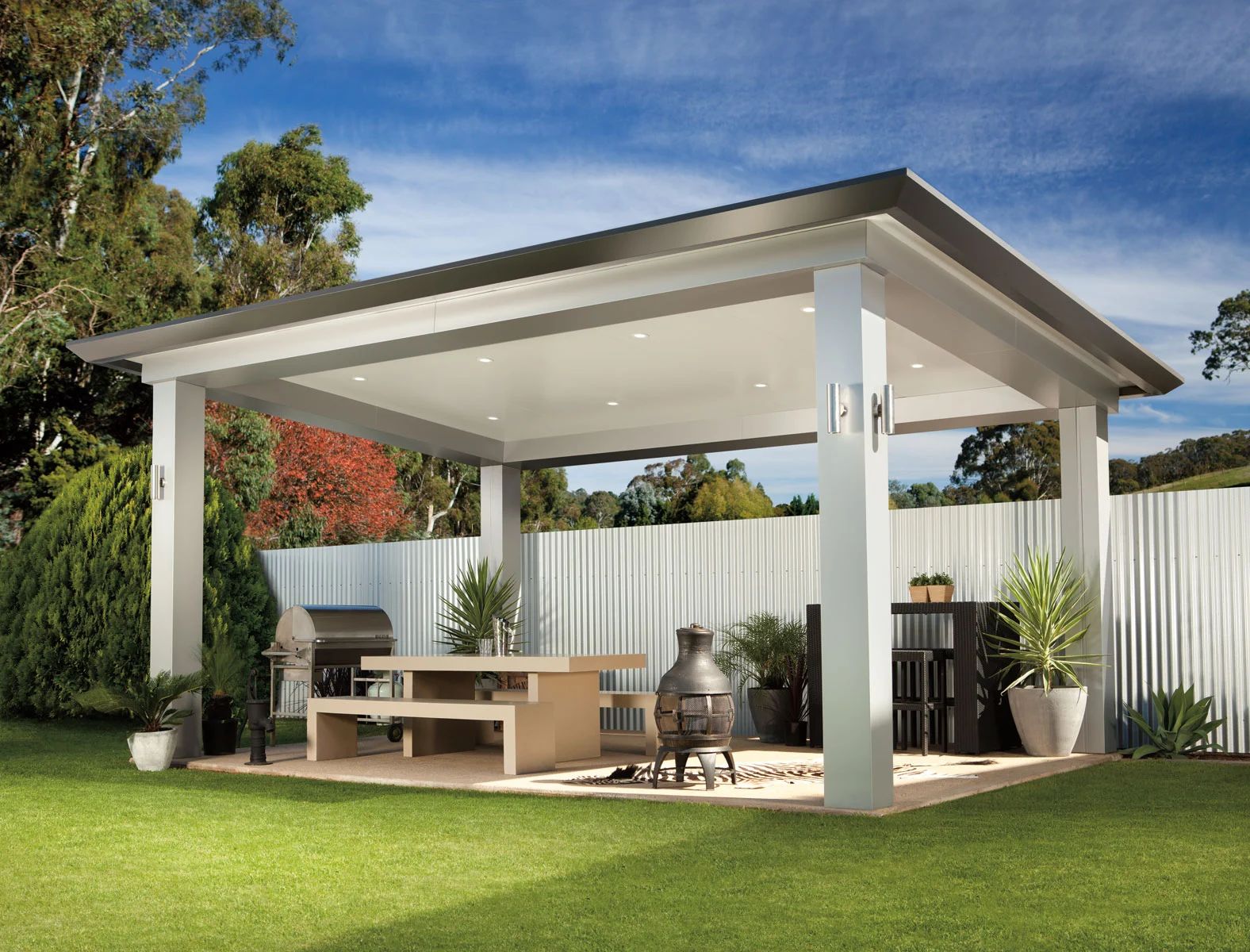 Modern white patio gazebo with seating on a green lawn under a blue sky