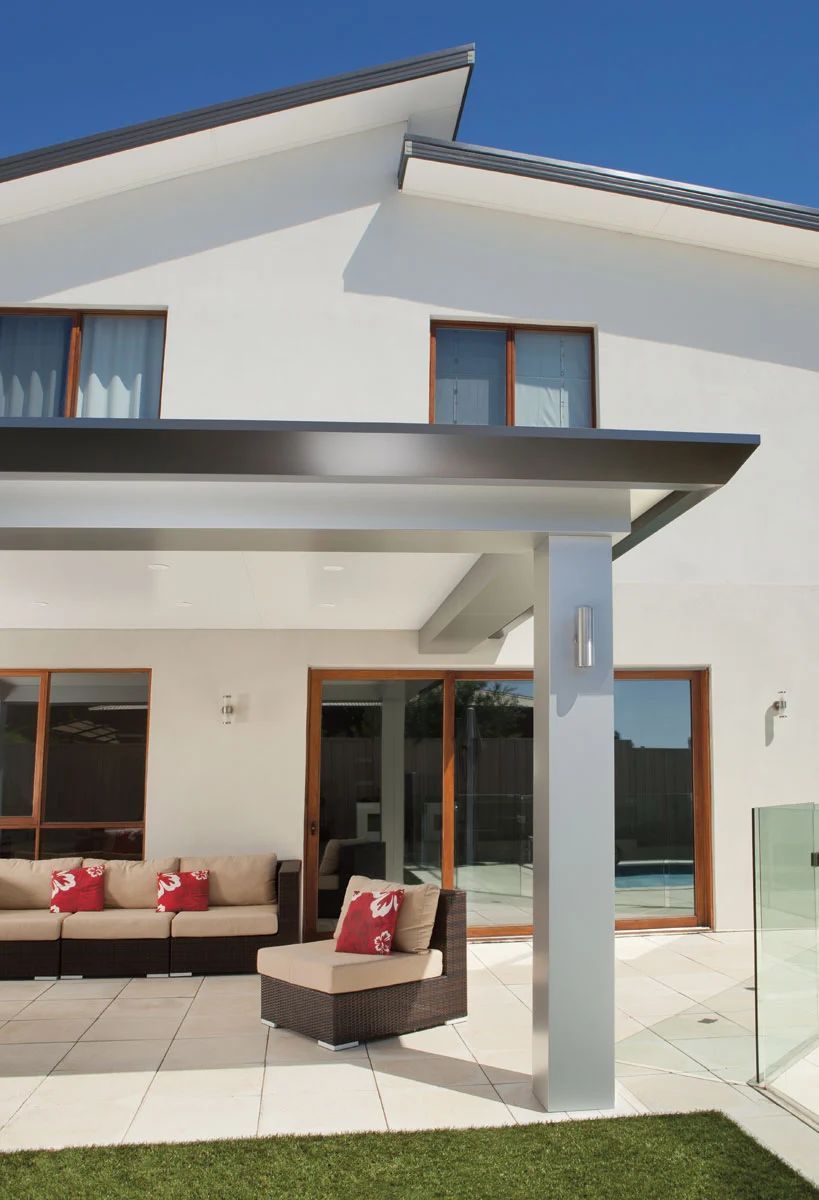 Modern white house patio with wicker seating and a glass-and-metal awning
